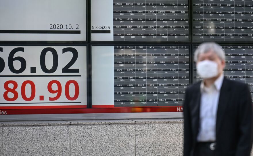 An electronic board displays stock prices near the Tokyo Stock Exchange in Tokyo on Friday. Markets were down somewhat after news that President Trump had tested positive for COVID-19.