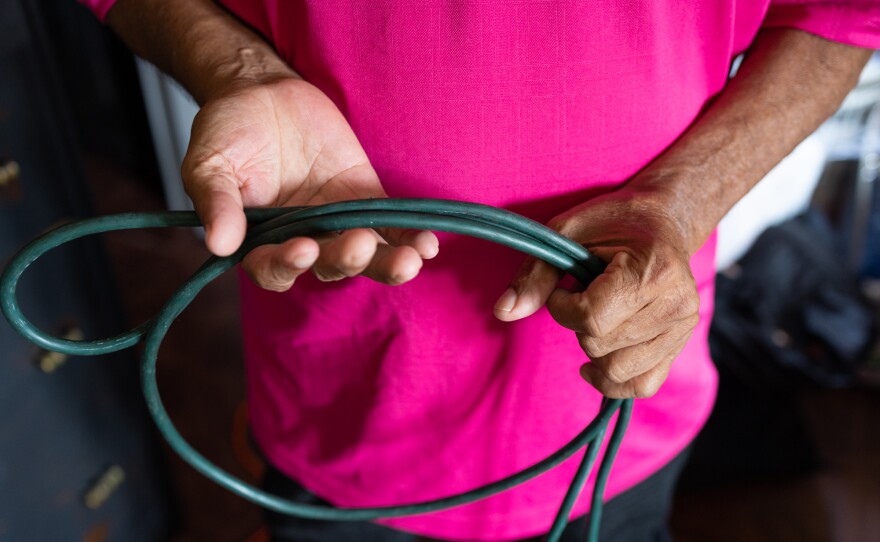 Jesús González shows the extension cable he uses to run power from the main outlet of the apartment into his bedroom to power the air conditioning unit. He says when it gets hot outside, most of the outlets in the building stop working because of the power demand.