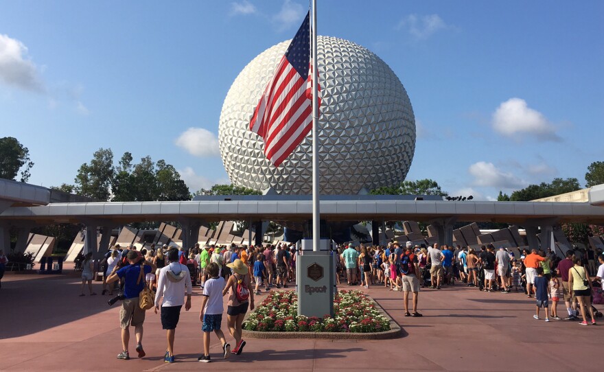 Tourists walk past the flag flying at half-staff at Disney's Epcot theme park in Orlando on Monday.