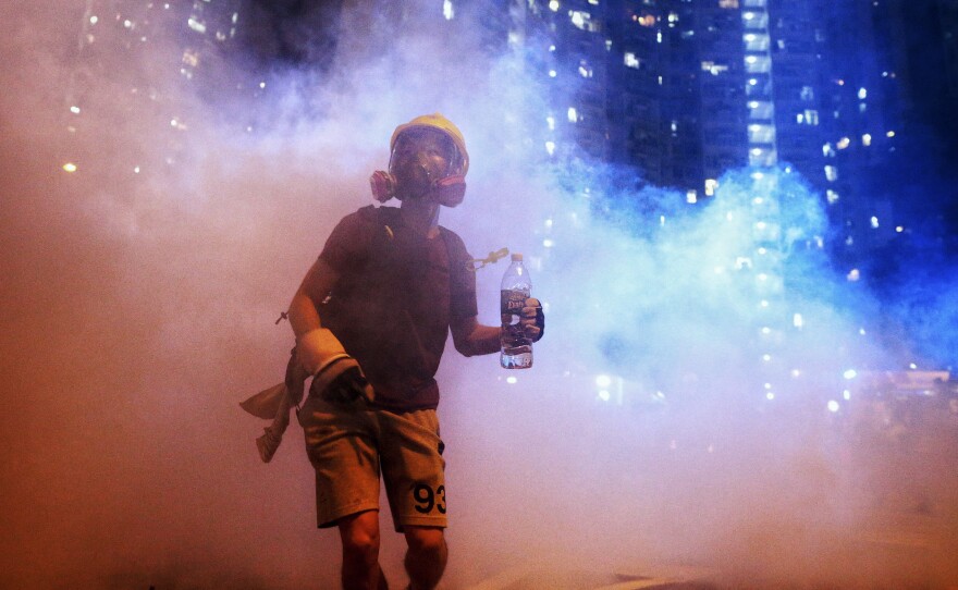 A protester stands in the midst of tear gas during a confrontation with police in Hong Kong during the early hours of Sunday local time.