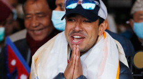 FILE - Nirmal Purja, one of the team members of the all-Nepalese mountaineering team that became the first to scale Mount K2 in winter, gestures as the team arrives at Tribhuwan International airport in Kathmandu, Nepal, Jan. 26, 2021.