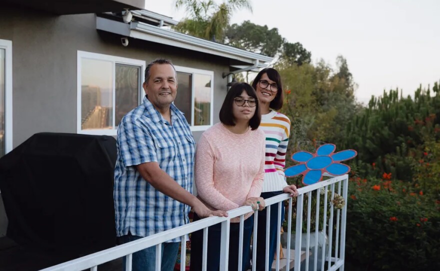 From left, Jack Deacy, his daughter Lena Deacy, and Lindsay Crain at their home in Culver City on Dec. 1, 2025. The family fears potential Medicaid cuts because Lena, who has cerebral palsy, epilepsy and other medical conditions, relies on Medicaid-funded services for her daily care and well-being.