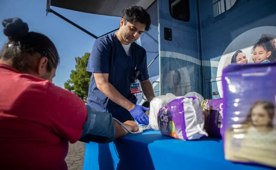 Dr. Ebraheem Quadri examines a patient in the parking lot outside the Saint Agnes Mobile Health Unit clinic, located in Rojas Pierce Park in Mendota on Aug. 28, 2025.