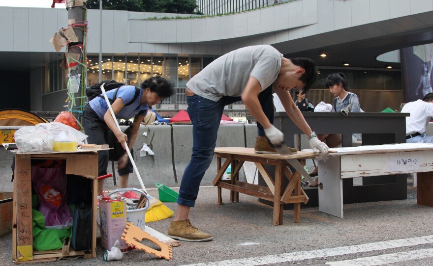 People with no past carpentry experience jump in to build tables and chairs from scrap wood so the students can continue their studies while protesting.