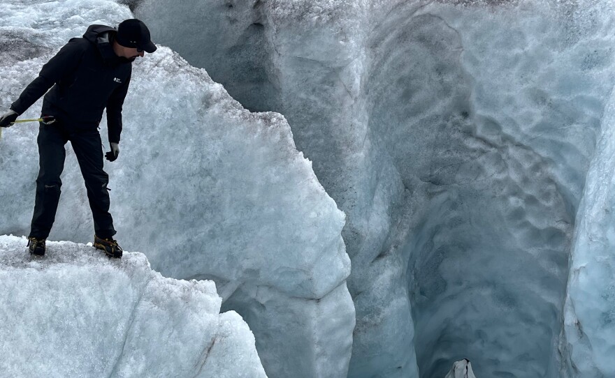 Aided with a rope, glaciologist Daniel Farinotti peers down a crevasse formed by glacial meltwater on the Rhône Glacier.