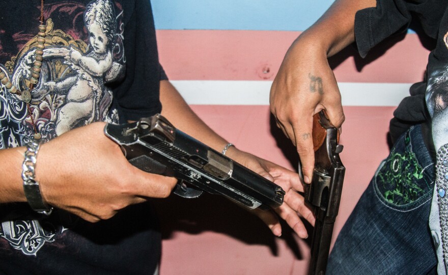 Before heading out on night patrol, gang members inspect their weapons in San Pedro Sula.