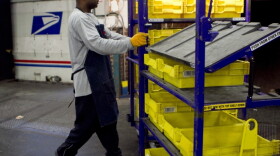 An employee loads flat trays onto a truck at the U.S. Postal Service processing and distribution center in Merrifield, Va. The USPS, which is projecting a $14.1 billion loss this fiscal year, is discussing restructuring options with potential advisers.