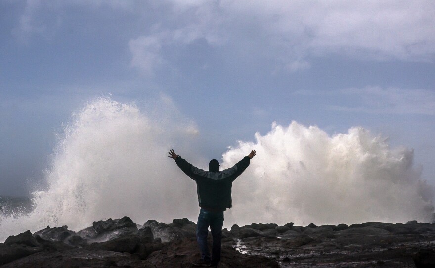 A man reacts as large waves caused by a bomb cyclone storm system break against the Oregon coast Sunday in Depoe Bay, Oregon. Heavy rain and wind may cause flooding in some parts of the region, but could aid areas of California struggling with wildfires.