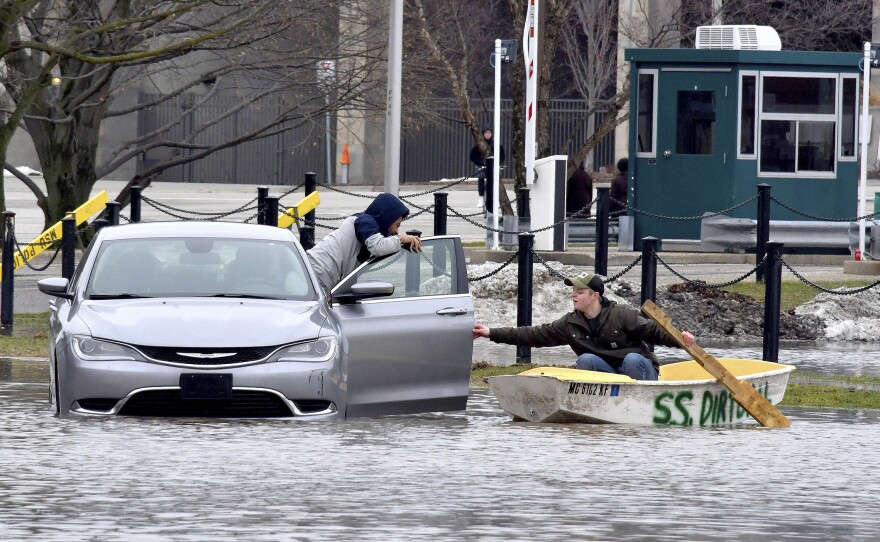 Mathias "Dale" Dekker (right) piloted his boat to rescue John Parker when the Red Cedar River flooded near Michigan State University in East Lansing on Wednesday.