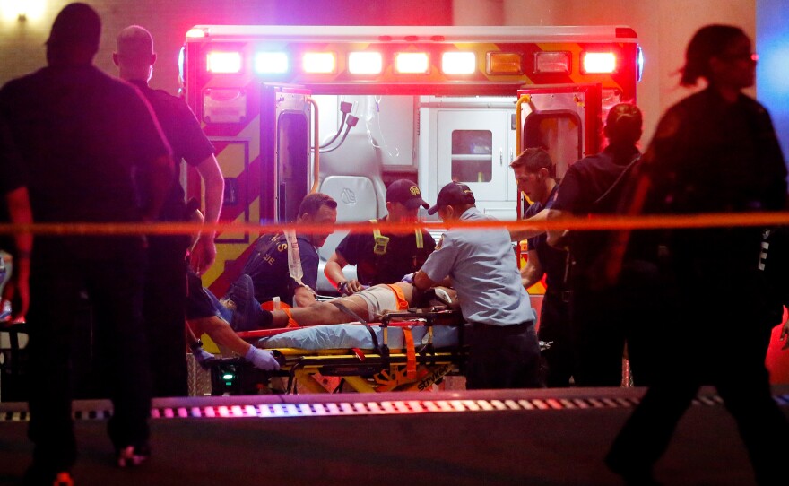 Emergency responders administer CPR to an unknown patient on a stretcher at Baylor University Medical Center as law enforcement officials stand nearby early Friday in Dallas.