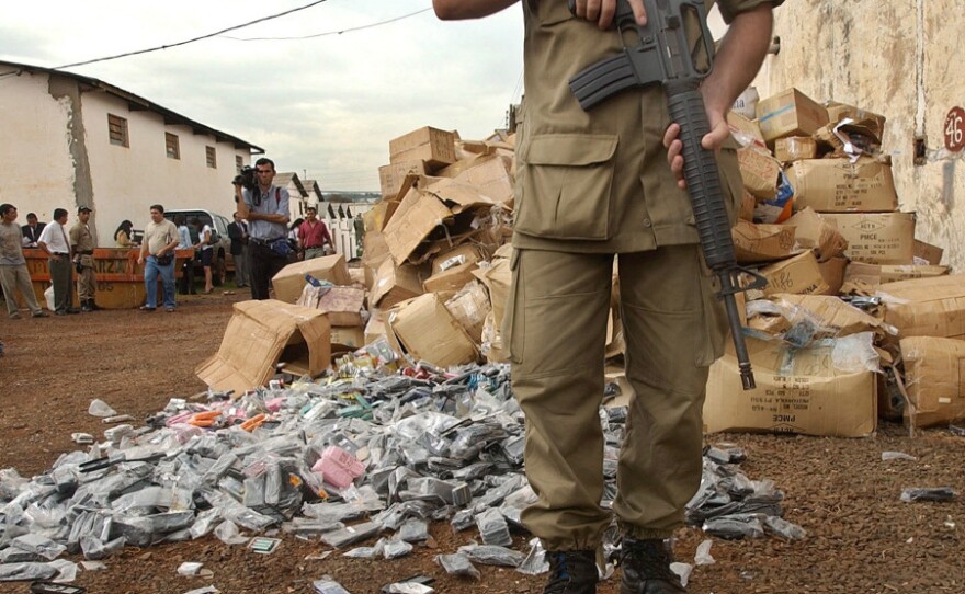 A police officer guards a stash of fake merchandise in Ciudad del Este,  Paraguay, the smuggler-ridden border town were Rotella sets part of his novel.