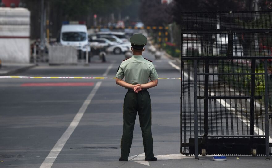 A law enforcement officer stands guard at the entrance of the Xinfadi market Saturday in Beijing. A fresh cluster of coronavirus cases linked to the market prompted officials to institute immediate and sweeping restrictions, including the market's closure.