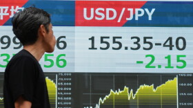 A person walks past an electronic board showing the U.S. dollar and Japanese yen exchange rate at a securities firm in Tokyo on Monday, Aug. 3, 2026.