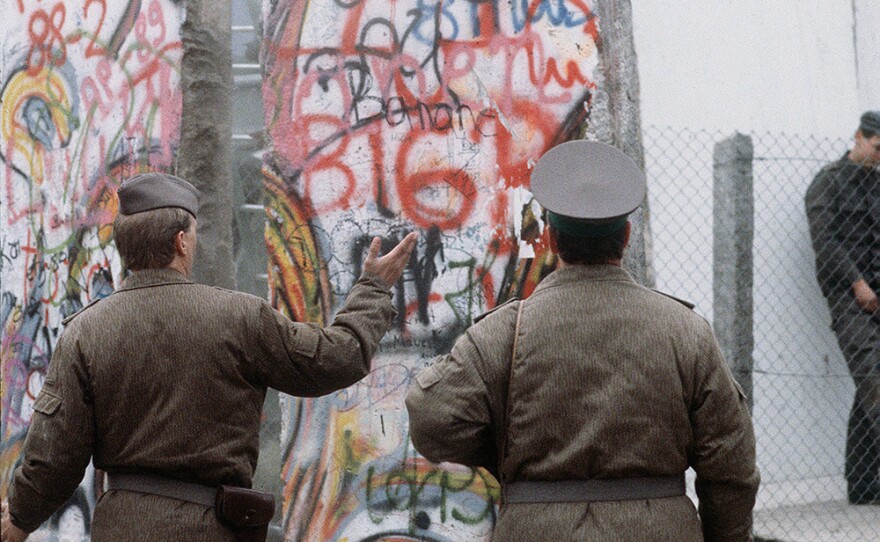 Standing on the West German side, East German policemen observe the newly created openingt in the Berlin Wall at Potsdamer Platz.