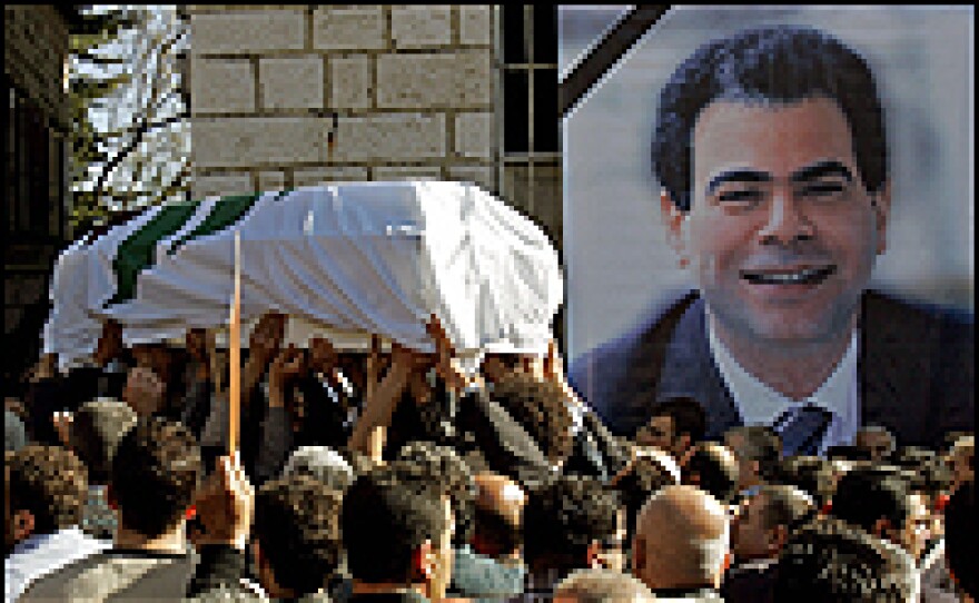 Mourners carry the coffin of Pierre Gemayel past his portrait in his hometown of Bikfaya.