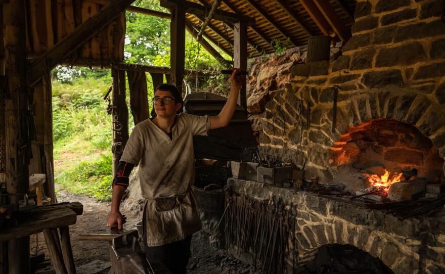 Matisse Lacroix, 20, a blacksmith at Guédelon Castle, works a large bellows to make the fire hot enough to melt iron and make it malleable.