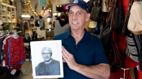 Director Rod Legg holds up a photo of Auntie Helen's founder Gary Cheatham inside the thrift store on Friday, Dec. 15, 2023.