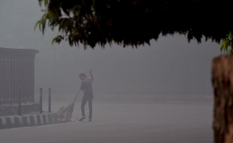 An Indian worker sweeps a street in a cloud of choking smog in New Delhi on Monday, the day after fireworks for the Diwali festival. After millions of firecrackers were lit, New Delhi's air pollutants shot up far higher than normal levels.