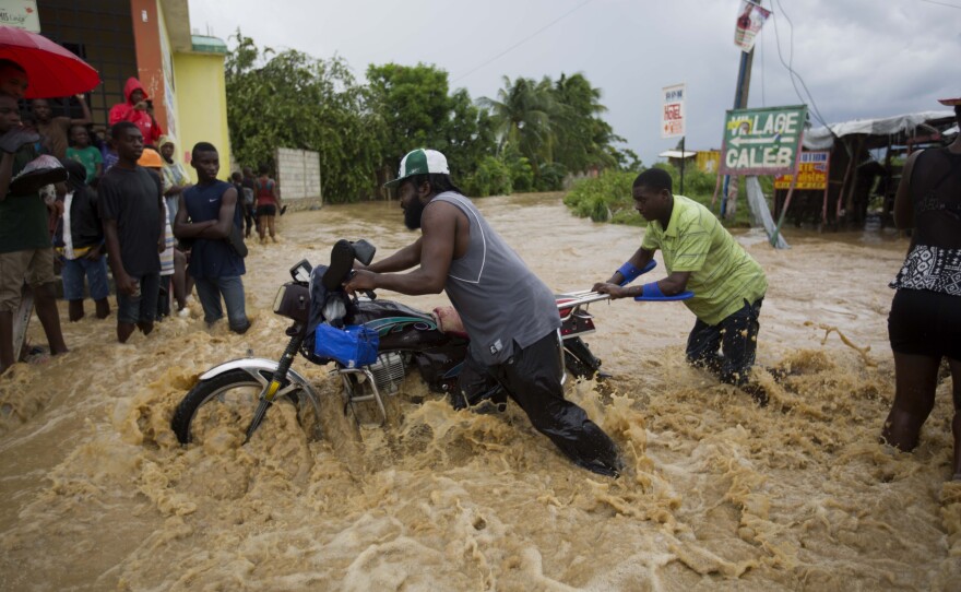 Men push a motorbike through a flooded street in Leogane, Haiti. U.N. peacekeepers already in Haiti spent Wednesday trying to clear local roads around Port-au-Prince.