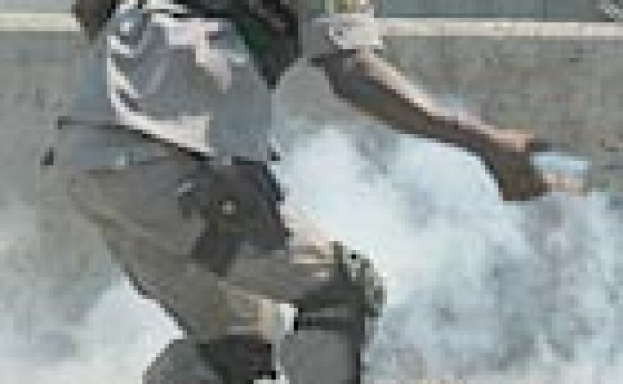 An anti-riot policeman throws a tear gas canister at protesters in a medical school near the U.S. consulate in downtown Port au Prince, Haiti.