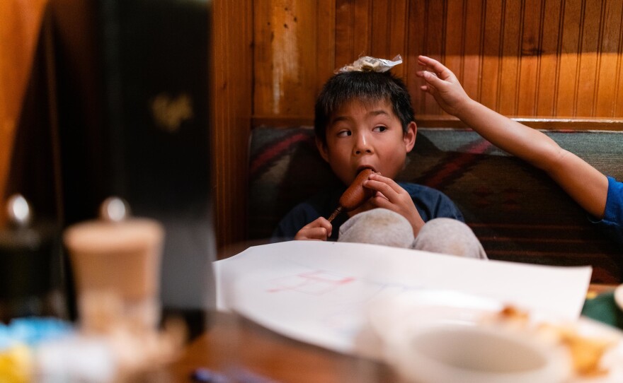 Hayle eats a corndog as Henry stacks oyster crackers on his head at Clyde's Tower Oaks Lodge in Rockville, Md., on Sept. 29, 2019.