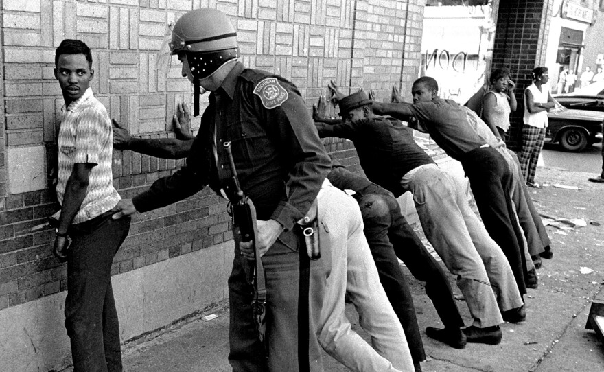 In this photo from July 24, 1967, a police officer searches a youth on Detroit's 12th Street.