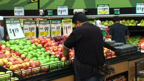 An employee checks the produce at the Food 4 Less in Market Creek Plaza on June 13, 2014.