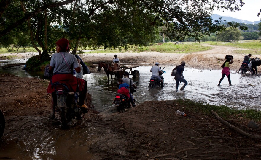 Colombian guides and migrants walk and ride motorcycles at the beginning of the journey through the Darién Gap. To cover the first few miles, migrants can pay to ride on the back of motorcycles that navigate muddy trails. But soon the jungle thickens, and they must start walking.