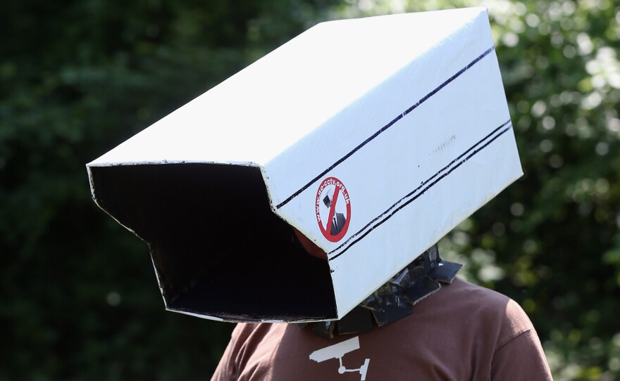 An anti-surveillance protester stands outside the Bilderberg conference last year in Watford, England. This year the conference may be in Denmark.