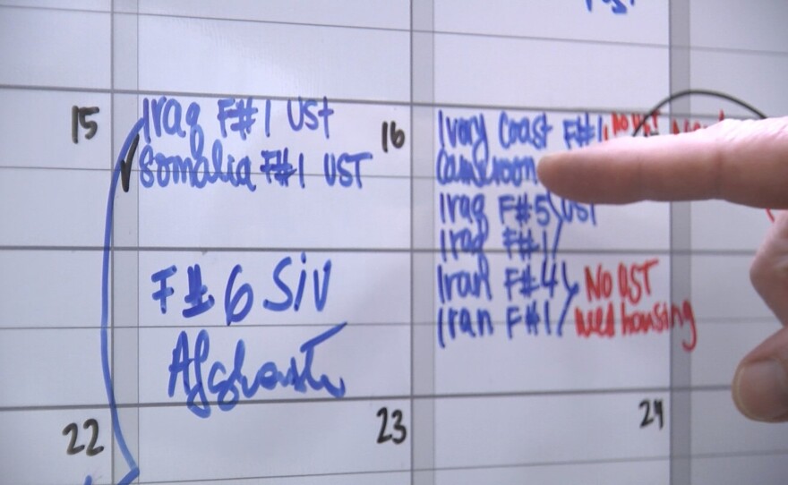 Catholic Charities Executive Director Robert Moser points to a whiteboard calendar that the agency uses to track refugee arrivals, Feb. 17, 2017.
