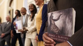 File photo of Dr. Amos C. Brown, Jr., vice chair for the California Reparations Task Force, right, holds a copy of the book Songs of Slavery and Emancipation, as he and other members of the task force pose for photos at the Capitol in Sacramento, Calif., on June 16, 2022.