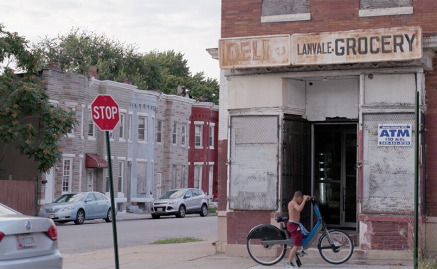 Young man sits on his bike in front of Lanvale grocery in Baltimore, Md.