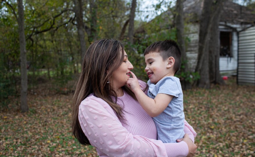 Ramona Bravo holds Azaiah, 2, in front of their house. Bravo spent 23 years in an abusive relationship and then lived at her parent's house.