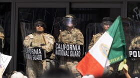 Demonstrators protest against recent ICE immigration raids as National Guard officers stand guard in front of a federal building in Los Angeles on June 9, 2025. CalMatters