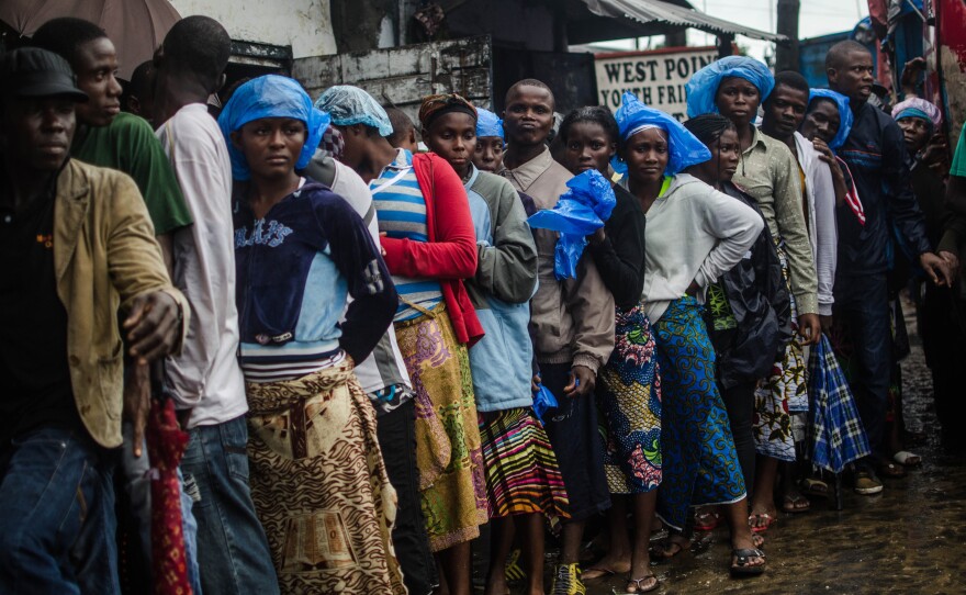 Recovering from the toll of the Ebola quarantine, residents of the West Point slum in Monrovia line up for food.