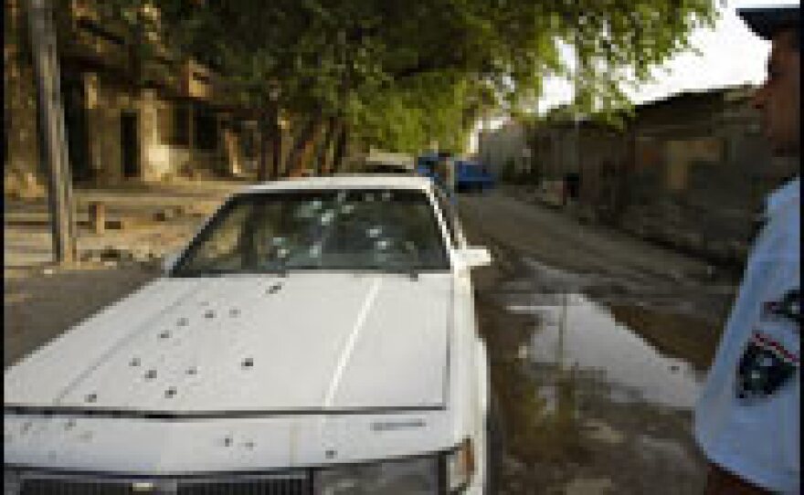 An Iraqi policeman stands by the bullet-riddled car of two women allegedly shot dead by private security guards in central Baghdad.