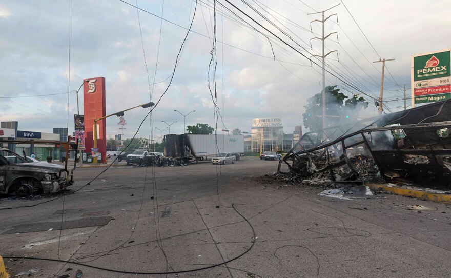 Burnt out vehicles used by gunmen smolder on an intersection, a day after street battles between gunmen and security forces in Culiacan, Mexico, Friday Oct. 18, 2019.