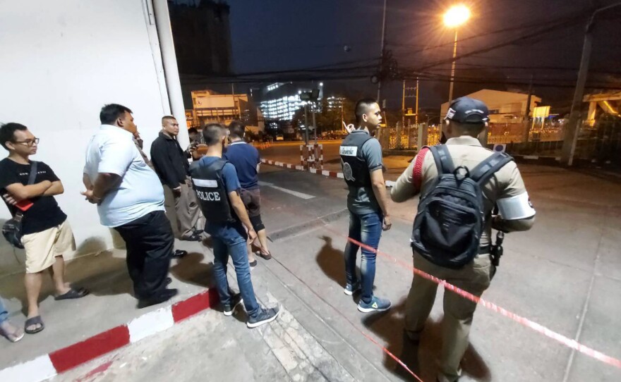 Police and bystanders stand near the scene of a shooting at the Terminal 21 mall, in Nakhon Ratchasima, Thailand on Saturday.