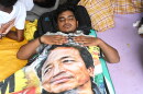 A reclining protestor covers himself with a banner printed with a portrait of Sonam Wangchuk, a prominent activist who was forcefully transferred to a hospital by the police as he staged a hunger strike in support of a movement led by Cockroach Janta Party, at a protest in New Delhi, India, Wednesday, July 22, 2026.