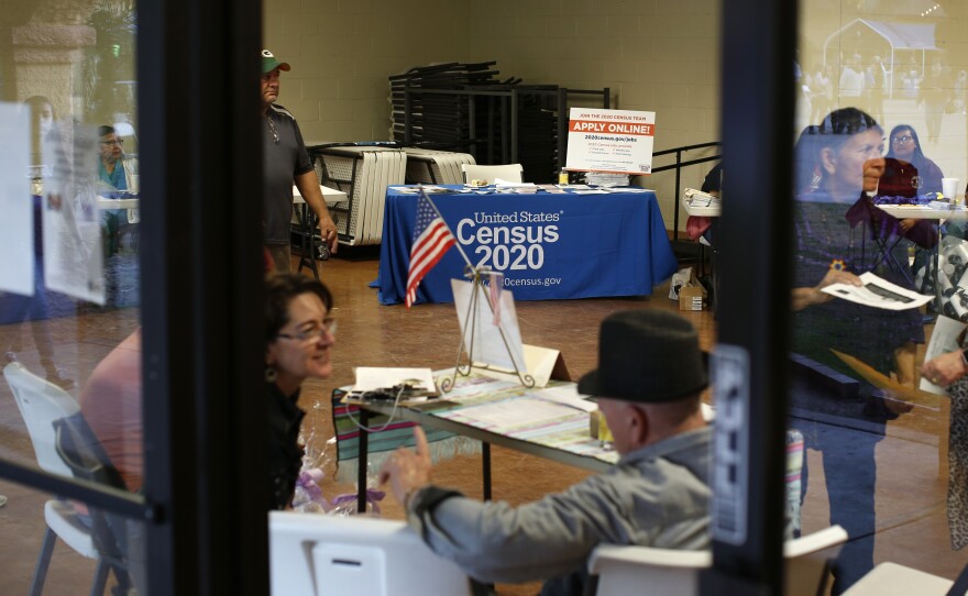 Volunteers at a February 2020 community event in Guadalupe, Ariz., gather near a table with information on how to apply for census jobs.