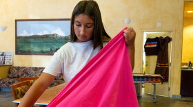 Talia Boller holds the fabric of her ribbon skirt on July 21, 2026.