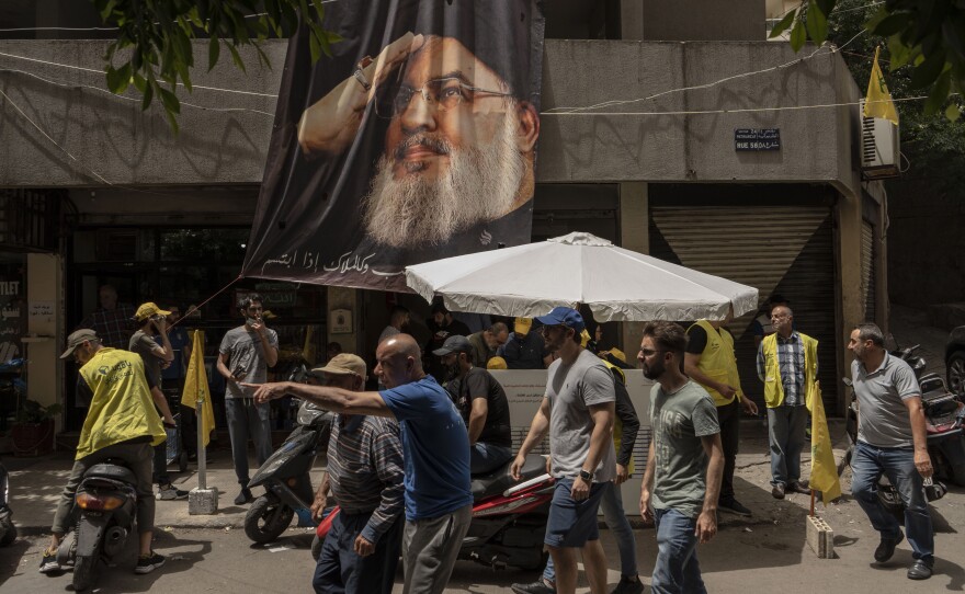 People pass a poster featuring Hassan Nasrallah, secretary general of the Hezbollah party, during parliamentary elections in Beirut, Lebanon, on May 15, 2022.