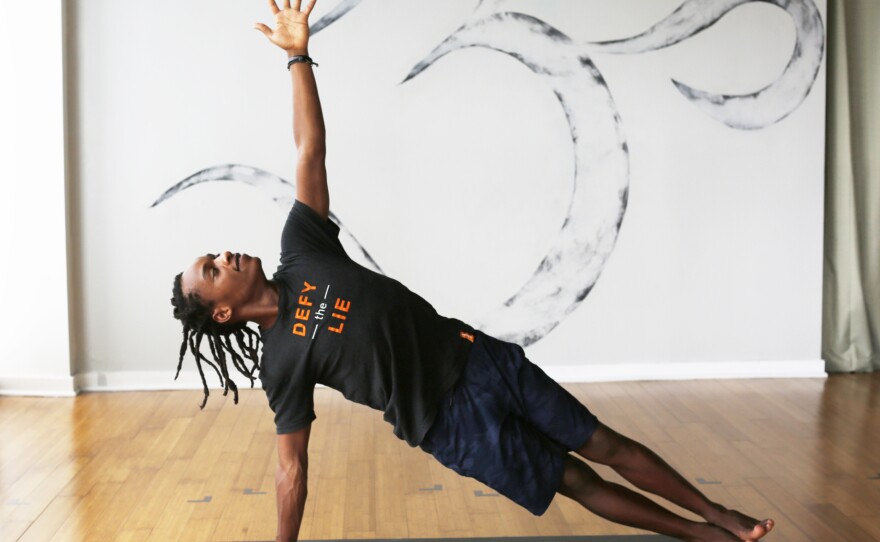 Walter Mugwe, a teacher with the Africa Yoga Project, demonstrates side plank in the Bethesda, Md., studio of Down Dog Yoga.