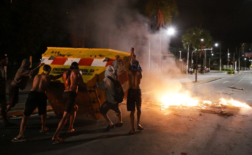 Young men tip a dumpster to make a barricade on Tuesday in Vitoria, Espirito Santo state, Brazil.