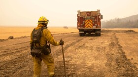 A Cal Fire firefighter watches for spot fires from a controlled burn at the edge of the Ranch Fire in 2018.