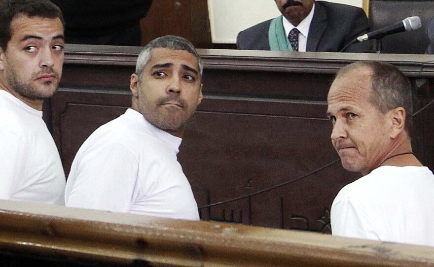 Al-Jazeera's Baher Mohamed (left), Mohammed Fahmy (center) and Peter Greste appear in court along with several other defendants during their trial on terror charges in Cairo. Egyptian President Abdel Fateh el-Sisi has criticized the killings of French journalists. But human rights groups cite the Al-Jazeera case as an example of Sisi's crackdown against critics, including journalists.