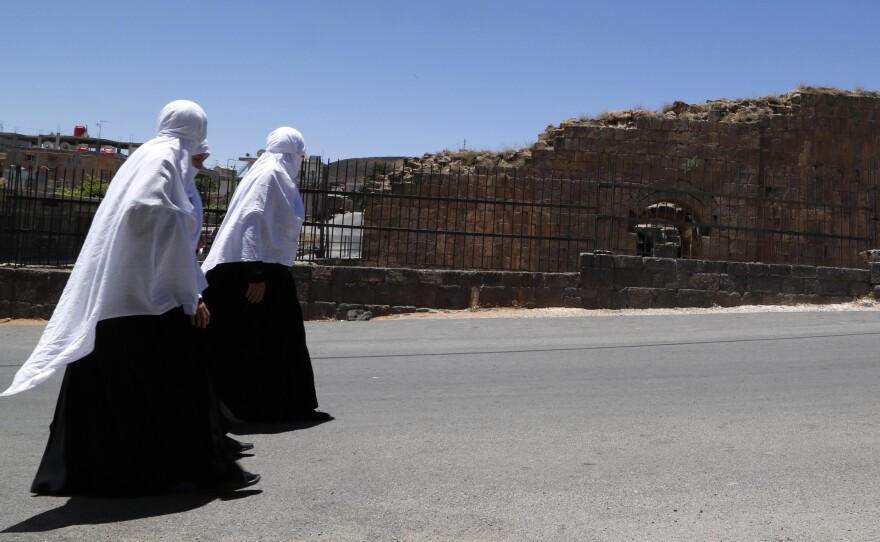 Druze women walk beside Roman ruins in Shahba, in southwest Syria, last June. The Druze are one of several minority communities that have generally tried to avoid direct involvement in Syria's civil war.