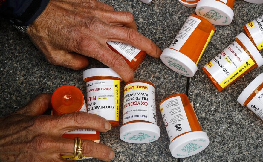 A protester gathers containers that look like OxyContin bottles at an anti-opioid demonstration in front of the U.S. Department of Health and Human Services headquarters in Washington in 2019.