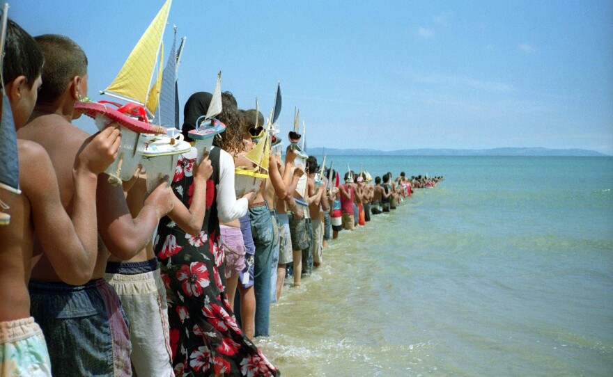 Children holding toy sailboats disappear into the water in Francis Alÿs' 2008 video <em>Don't Cross the Bridge Before You Get to the River (Strait of Gibraltar, Morocco-Spain).</em>
