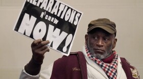 Globally, attitudes toward reparations are changing, experts say. Morris Griffin (pictured) holds up a sign during a meeting by the Task Force to Study and Develop Reparation Proposals for African Americans in Oakland, Calif.